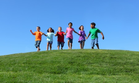 child and youth opportunity: happy children running over grassy hilltop towards camera