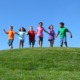 child and youth opportunity: happy children running over grassy hilltop towards camera