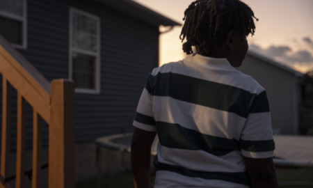 11-year old juvenile arrest for making threat in Tennessee: view of young black child from behind in horizontal striped shirt at dusk