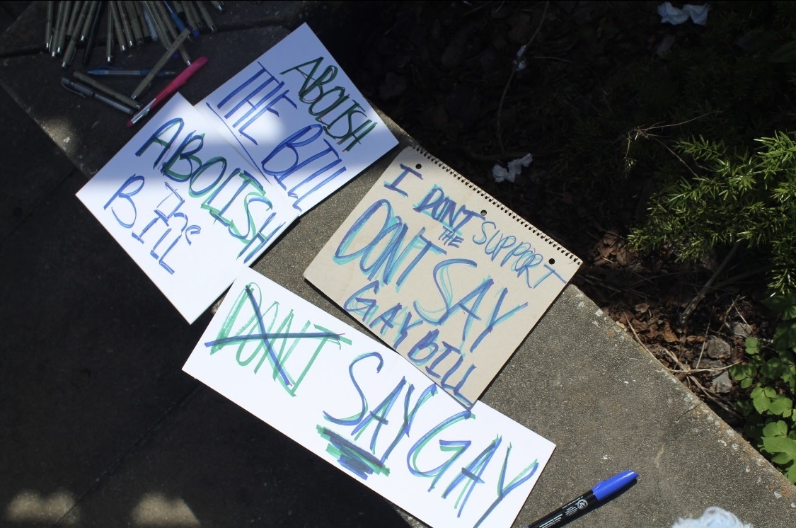 New Florida policy could out LGBTQ students to their parents: protest signs laid out on the ground with marker next to them