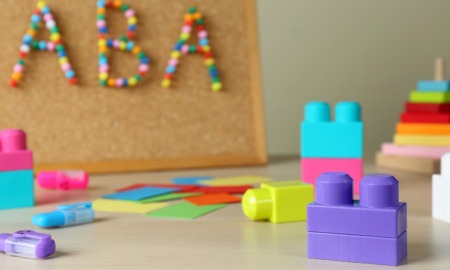 America’s most popular autism therapy may not work and may seriously harm patients’ mental health: cork board with "ABA" spelled out and colorful building blocks in foreground