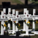 School shootings: White crossed with names in black paint and flowers on them in grassy area