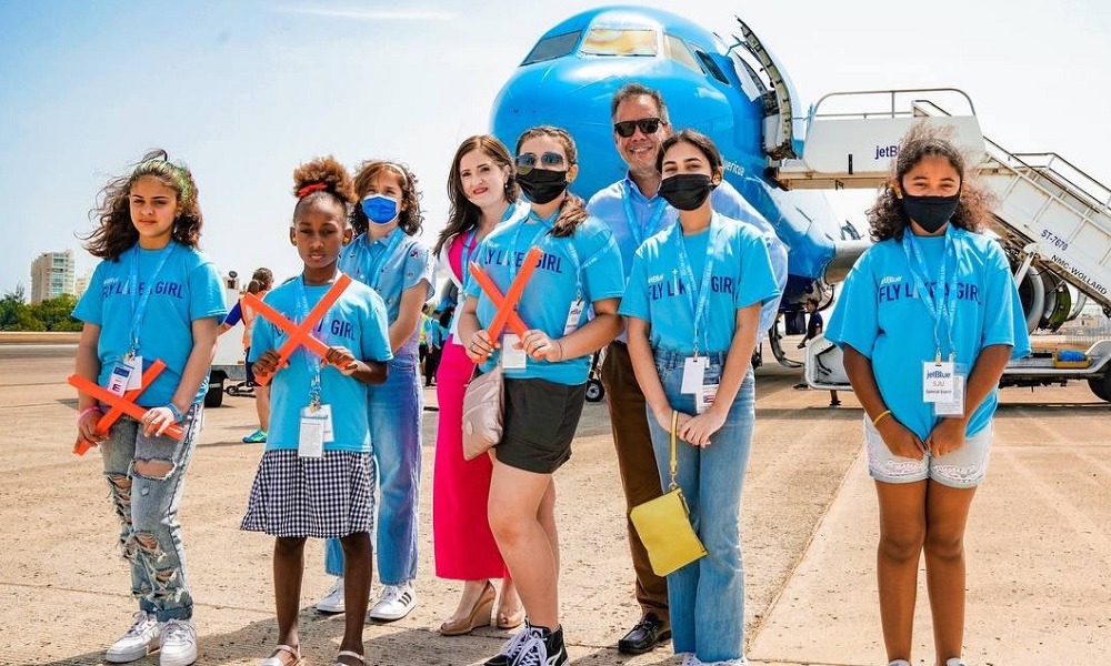 aviation education grant: group of girls in bright blue shirts standing in front of plane on tarmac