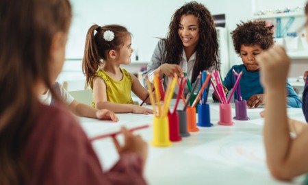 campus-based child care access grants: young woman works with children at table with lots of colored pencils