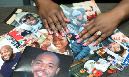 COVID families: Black woman's hands wearing a wedding ring lsort through several color photos overlapping laying on a table.