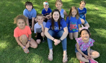 SEL - A person with long hair and children sit on the grass