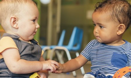 Kids' share report on federal expenditures: small white boy and small black boy playing with building blocks together touching hands