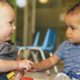 Kids' share report on federal expenditures: small white boy and small black boy playing with building blocks together touching hands