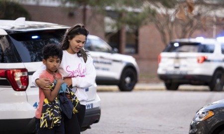 teacher shot by 6-year old 'red flag' for country: mother and frightened child stand outside next to police cars