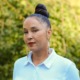 Michaela Pommells headshot: woman with dark hair up in bun and colorful earrings standing outdoors