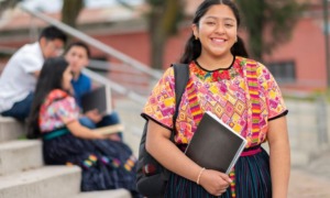 Native youth, tribal higher education student support grants: young native woman with backpack and notebook smiling on steps outdoors