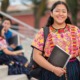 Native youth, tribal higher education student support grants: young native woman with backpack and notebook smiling on steps outdoors