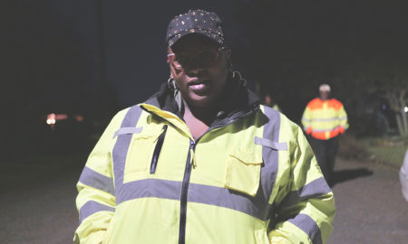 gun violence: Woman in yellow jacket, blue cap looks straight into camera