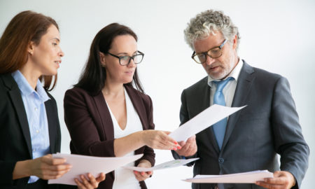 toolkit: Woman showing papers to man and woman in suits.