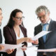 toolkit: Woman showing papers to man and woman in suits.