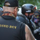 white nationalism: Rear view of man in crowd wearing ball cap, blue tank top that says Proud Boy.