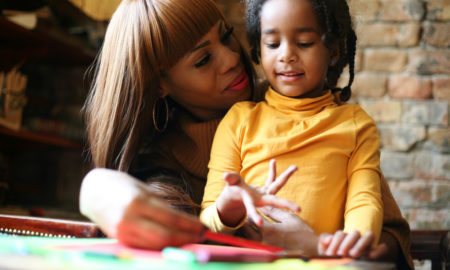 Foster care racism: Black woman with young Black child sitting at table doing homework.