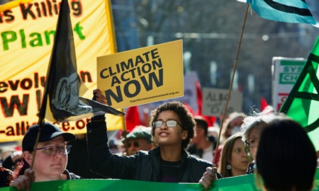 Climate change protest: Young people in street carrying protest signs about climate change