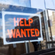 ODT Hiring: Black and orange Help Wanted sign in glass window