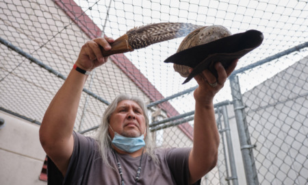 Native American rituals: Native American relder man with long gray hair ho,ding plate of smoking dage and using eagle feather to disperse the smoke