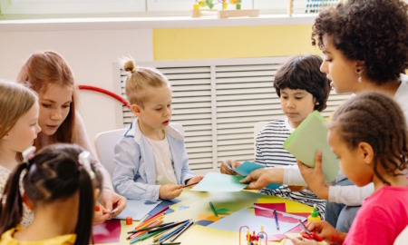 Califonia pre-kindergarten: Five young children sit at round table with two fenale teachers doing art activities