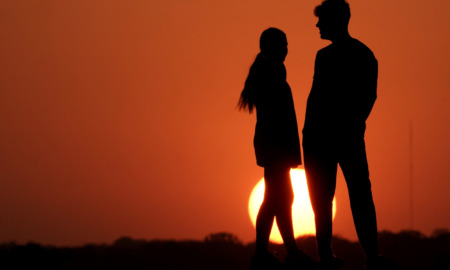 Teen sex: Two people are silhouetted against a deep orange sky as the sun sets