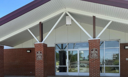 Juvenile solitary confinement: Lathe one-story red brick building entrance with pillars, white trim and triple glass doors.