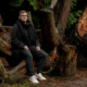 Homeless lifeline Washington state: Man with brown hair in dark pants and winter jacket leans against tree on park pathway