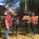 Disability rights: A smiling woman sits atop a dark brown horse. Two other smiling women stand on the ground on either side of the woman on the horse.