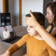 Telemedicine and absenteeism: Mother sits at table with hand on forehead of preteen age son in her lap looks at doctor on laptop screen