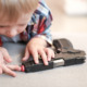 Gun Safety ar Home: Very young boy leans close to hand fun on table poking one finger into barrel.