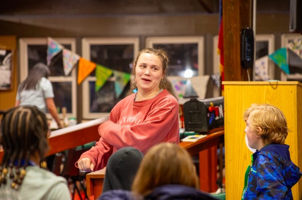 Georgia summer camp for disabled youth: A woman with tied-back brown hair wearing a red sweatshirt dances with a group of children dressed in casual clothing.