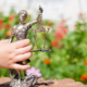 Legal counseling for behavior issues: Young child's hand holding sculpture of themis, femida or justice goddess on green leaves natural bokeh copy space background