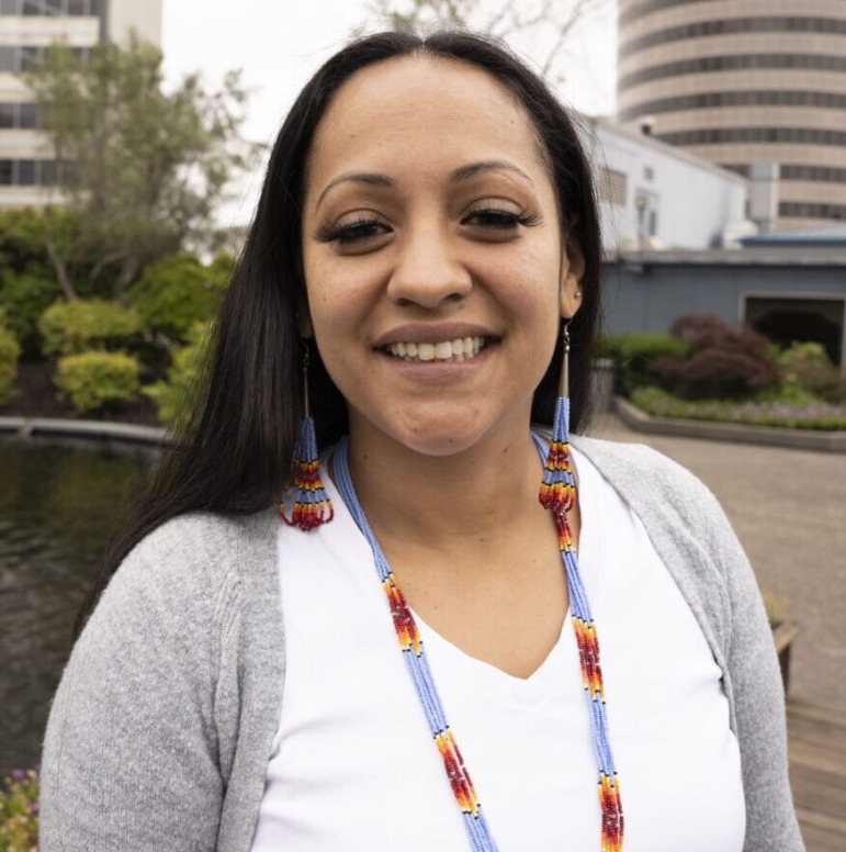 CA foster care shutdown: Woman with long dark hair in white blouse and gray sweater smiles widely into camera