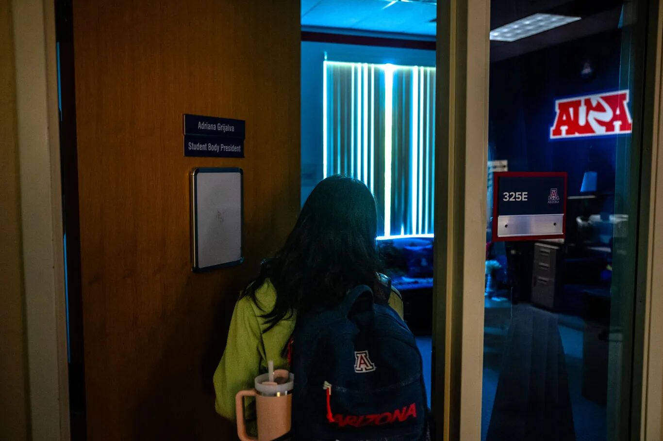 Latino voters gun reform Arizona: Person with long dark hair enters office doorwat with back to camera