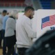 School choice votes: Several people stand in partially enclosed voting booths writing on table top