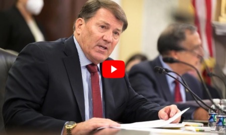 Shut down US DOE: Sebn. Mike Rounds, Reb. from S. Dakota -- a middle -aged man in navy suit and light blue shirt with red tie sits at dark wood table speaking into a microphone.