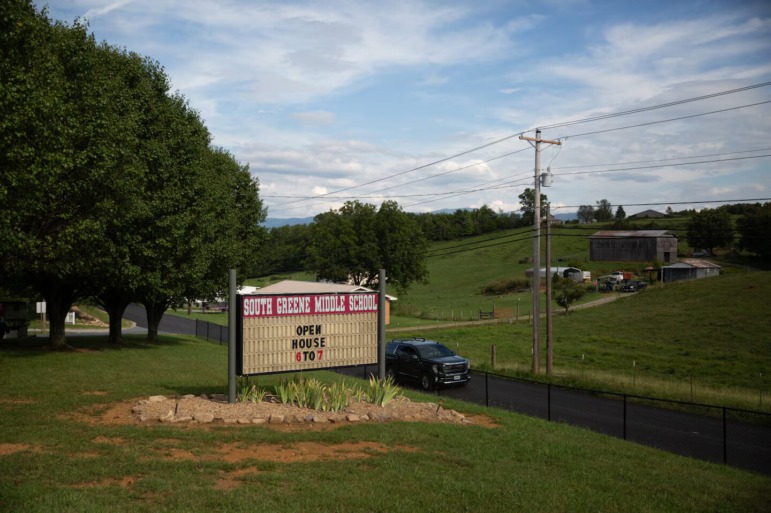 Arming teachers in Tennessee: South Greene Middle School sign with open house times sits in large green grassy area next to a rural road surrounded by grass pastures and trees