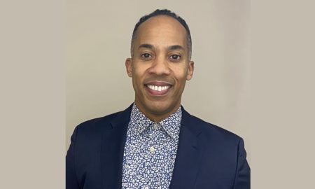 Ivan Heredia newsmaker headshot; smiling man in suit jacket and patterned, collared shirt