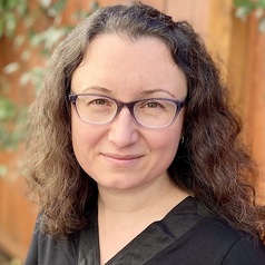 Cannabis dispensary near schools: Headshot woman with long light brown hair and wire frame glasses in black top