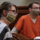 Parents of teen charged in school shooting to stand trial: middle-aged white man and woman in facemasks sit at hearing