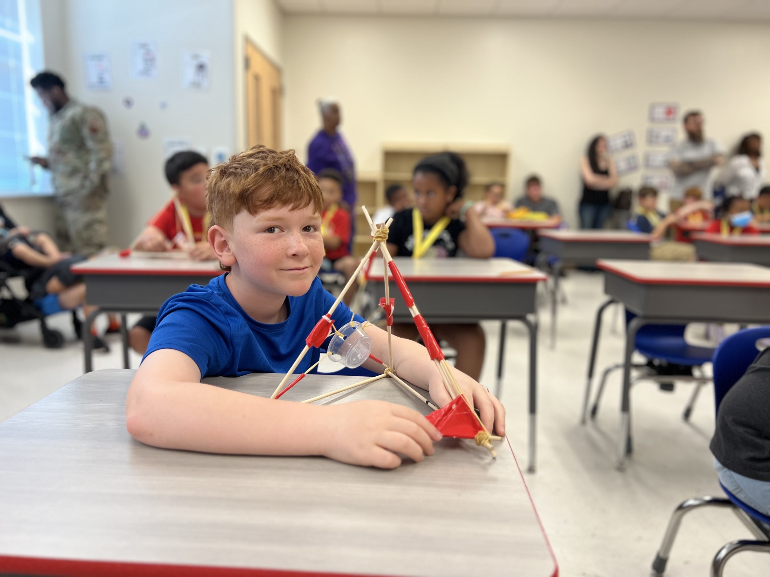 Post-COVID summer programs: young male student at desk shows his pyramid-shaped project