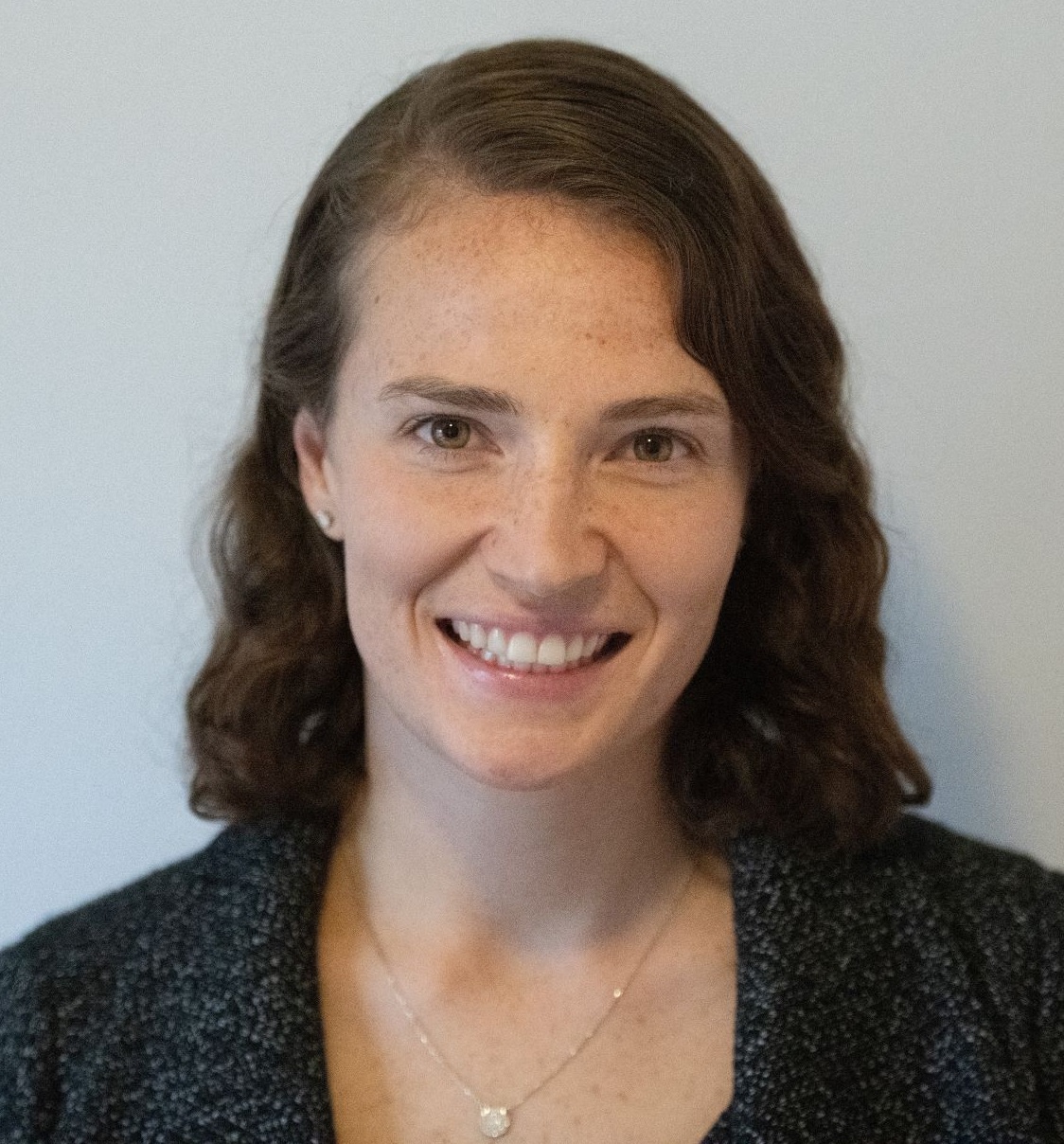 Post-COVID summer programs: white woman with mid-length brown hair in front of grey background