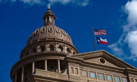 State laws threaten academic freedom in higher education: view looking up at Texas state capitol building with U.S. flag and Texas flag flying