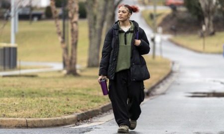 The pandemic missing; kids who didn't go back to school: black female student in large clothes walks down street with backpack and drink