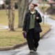 The pandemic missing; kids who didn't go back to school: black female student in large clothes walks down street with backpack and drink