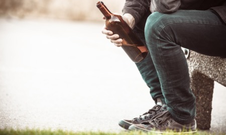 underage drinking prevention and reduction grants: youth sitting on bench drinking from bottle of wine