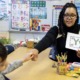 US teacher shortage, HBCU helping to change that: young Black female teacher fist bumps a student while teaching