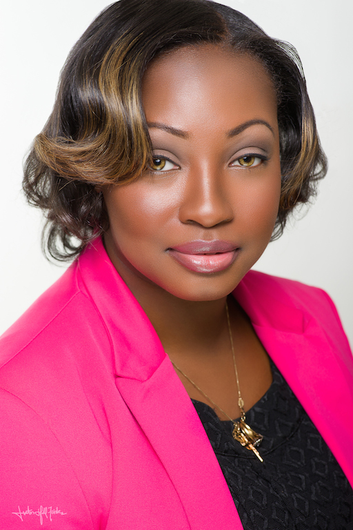 Jaynemarie-Angbah headshot: clack woman with short brown hair in hot pink jacket & black top